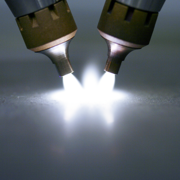 two plasma torches generate a bright, radiant arc on a surface. two plasma torches generate a bright, radiant arc on a surface.